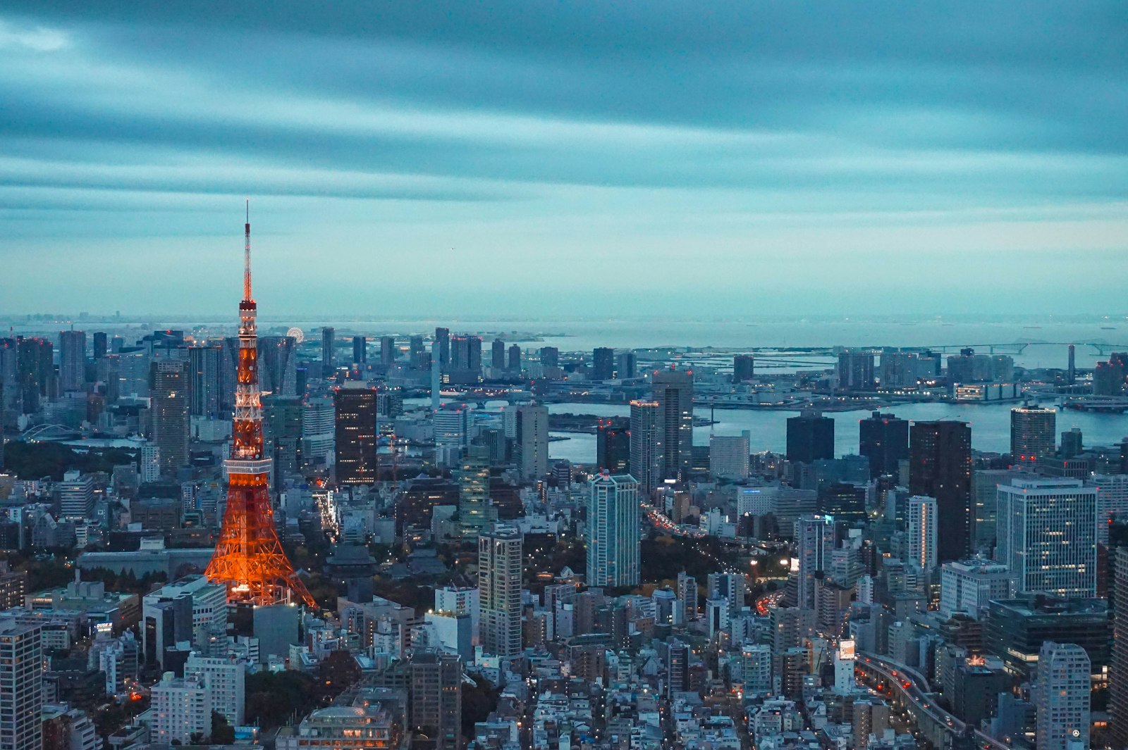 Tokyo Tower lit up at dusk above the city skyline